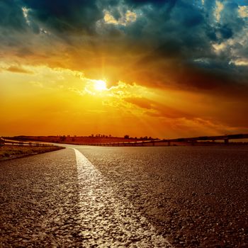 dramatic sunset and white line on asphalt road to horizon