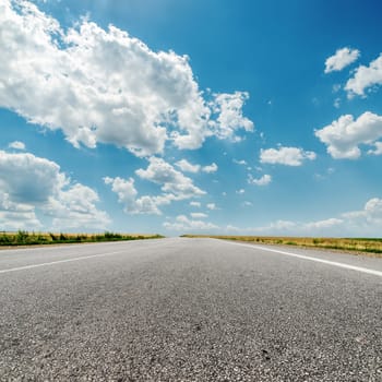 asphalt road to horizon and clouds over it