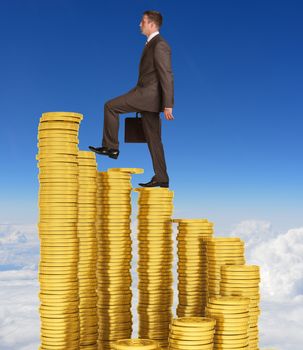 Businessman climbing stairs of gold coins. Sky and clouds in background