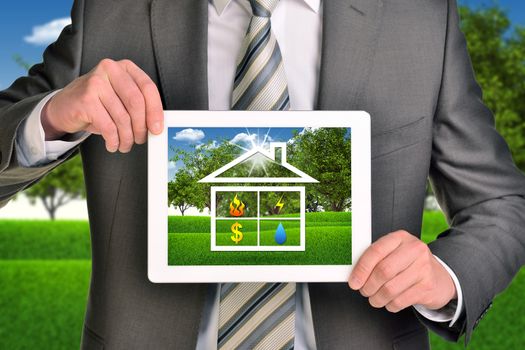 Two hands holding tablet pc. Picture of house icon on screen. Blured nature landscape on background