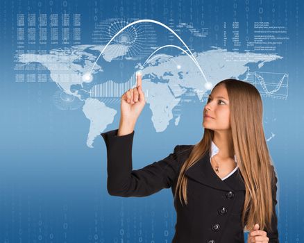 Beautiful businesswoman in suit presses finger virtual map of the world. Graphs and figures as backdrop