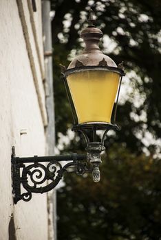 An antique wrought iron lamp hanging on a white castle brick wall