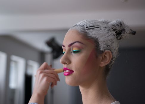 Model applying make up and preparing for photoshoot