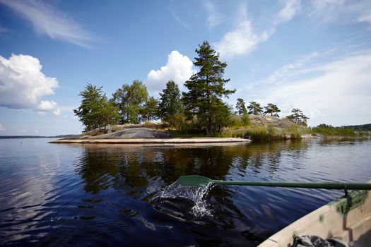 Island in the lake. Water landscape with stones. Stones in water. The lake with stones. Beautiful landscape. Water smooth surface and the blue sky with clouds.