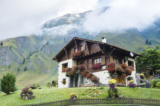 FERRET, SWITZERLAND - AUGUST 30: Beautiful chalet decorated with flowers and with mountains in the background. The village is a stage of the Mont Blanc tour. August 30, 2014 in Ferret.