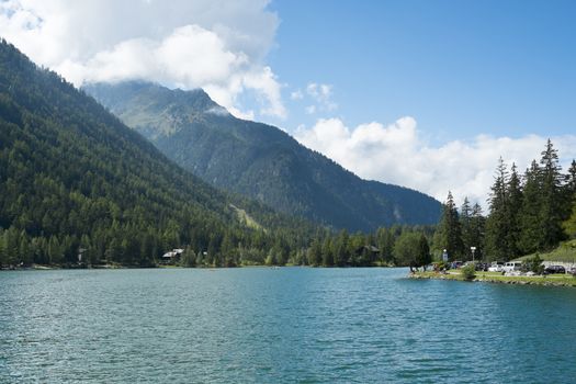 CHAMPEX, SWITZERLAND - AUGUST 30: Placid lake with tree covered mountains in the background. The village is one of the Mont Blanc tour stages. August 30, 2014 in Champex.