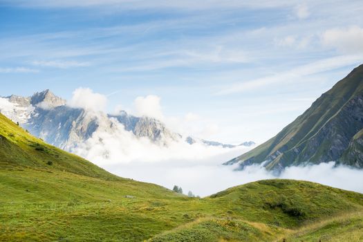 Low hanging clouds in La Peule valley, in Switzerland, with alps in the background. The region is one of the stages in the popular Mont Blanc tour, which crosses France, Italy and Switzerland.