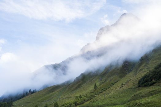 Clouds rolling down hillside in les Ars Dessus, Switzerland. The region is one of the stages in the popular Mont Blanc tour, which crosses France, Italy and Switzerland.