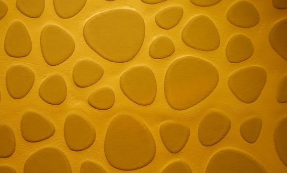 Background of Golden Sand Colored Droplet Shaped Stone on Cement Wall closeup