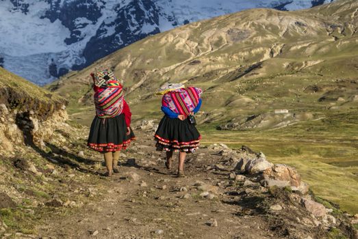 Close-up view of two Peruvian woman walking along the path in Peruvian Andes         