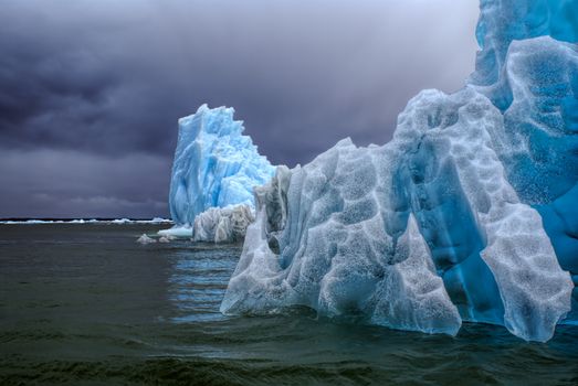 Glaciers floating in the ocean               under cloudy grey sky in Laguna San Rafael