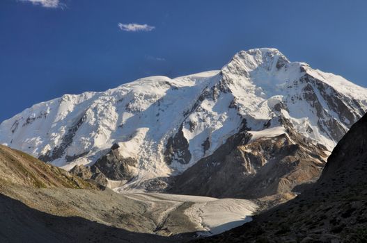 Panoramic view of sunlit snow-covered slopes of Tian-Shan Mountains, Kyrgyzstan