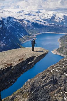 Hiker peering over the edge of Trolltunga rock, Norway