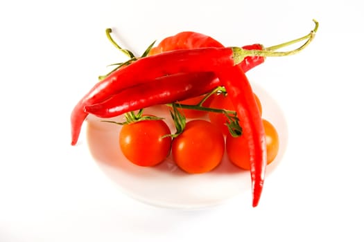 Photo presents details of red tomatoes and peppers on the white background.