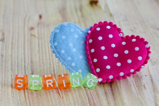 Photo shows details of spring sign with heart on the wooden background.