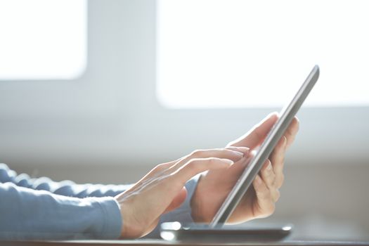 Human hands using tablet computer at home