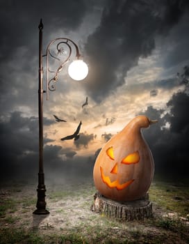 Halloween pumpkin on the stump and streetlamp