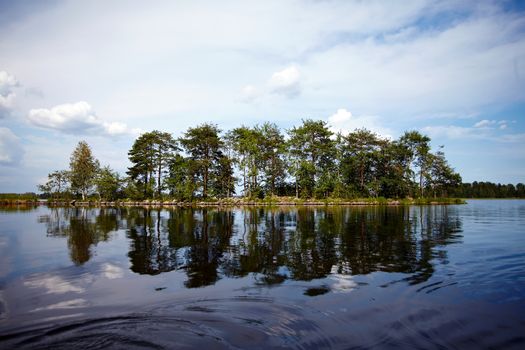 Water landscape. The lake. Beautiful landscape. Water smooth surface and the blue sky with clouds.