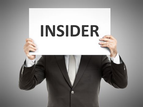 A business man holding a paper in front of his face with the text insider