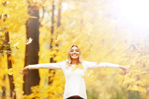 Happy woman posing in autumn park on yellow trees background