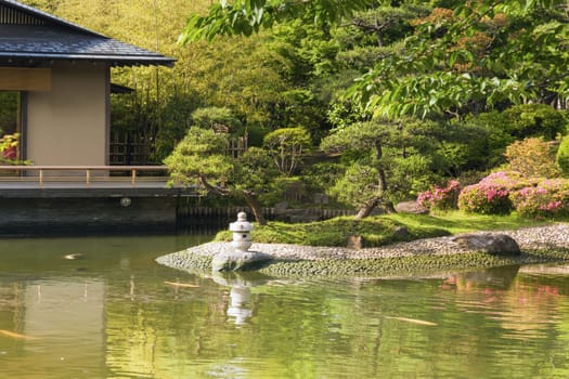 scenic Japanese zen garden with pond and small stone lantern by summer