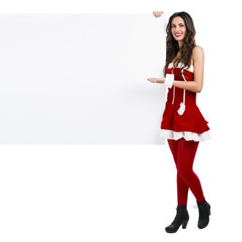 Beautiful and sexy woman wearing santa clause costume and holding a blank billboard

