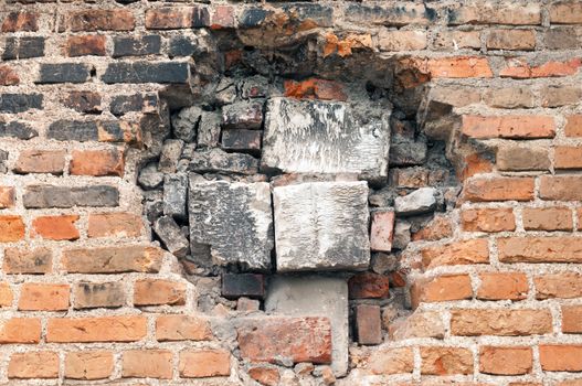 big hole in the old brick wall immured by different block pieces