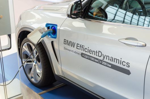 MUNICH, GERMANY - AUGUST 8, 2014: New model of environmentally friendly electric car BMW x5 with hybrid engine at charging station.