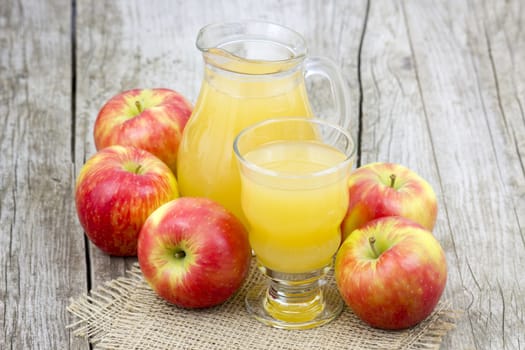 Apple juice and apples on wooden background