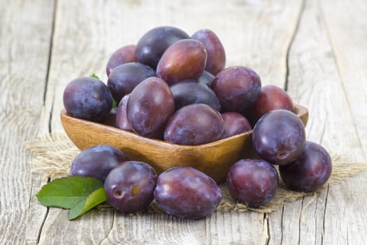 fresh plums in a bowl on old wooden background