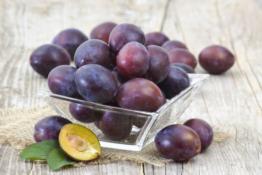 fresh plums in a bowl on old wooden background