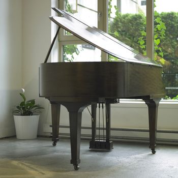 Brown baby grand piano in a white room