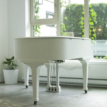White baby grand piano in a white room