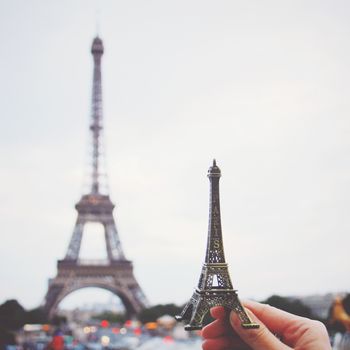 Hand holding eiffel tower model in paris, retro filter effect