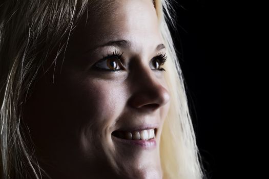 laughing  young blond woman against black background