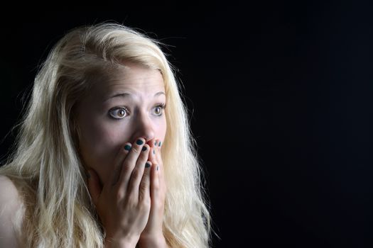 surprised young  woman in front of black background