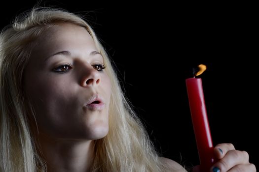 beautiful young blond woman blowing candle