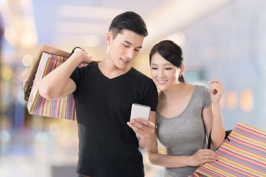 Young Asian couple shopping and looking at cellphone, closeup portrait.