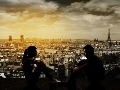 Silhouette of young couple face to face sit on ground in the city night.