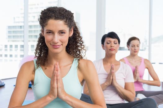 Portrait of sporty young women with joined hands at a bright fitness studio