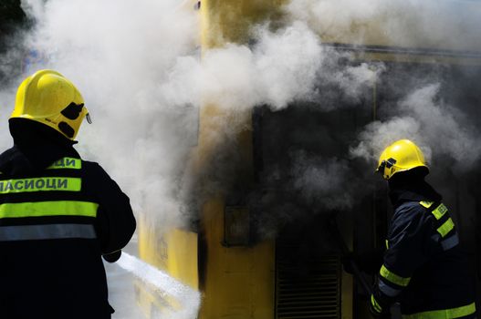 SERBIA, BELGRADE - APRIL 27, 2012: Fire fighters tries to extinguish burning bus on the street