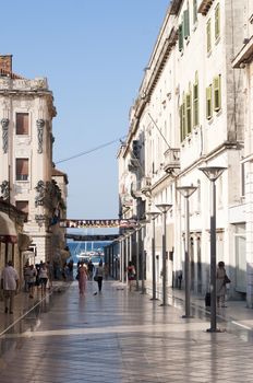 CROATIA, SPLIT - AUGUST 8, 2011: People walk the old town street in the morning in Split. Milions of tourists visit Croatia every year, most of theim in summer