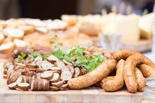 Dry sausage cold cuts. A variety of dry cold smoked meat products with herbs and mustard and  horseradish spreadon a wooden cutting board. 