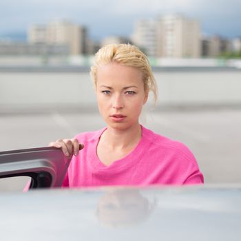 Portrait of responsible female driver holding car keys in her hand. Safe driving school.