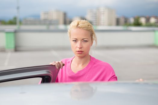 Portrait of responsible female driver holding car keys in her hand. Safe driving school.