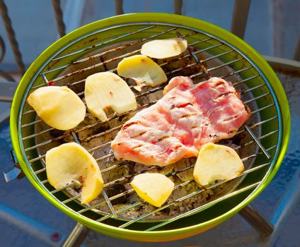 Beef and potatoes over barbecue, close up