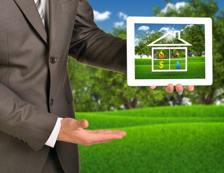 Two hands using tablet pc. Picture of house icon on screen. Blured nature landscape on background