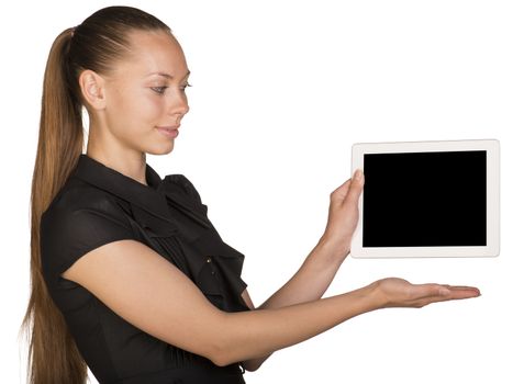 Beautiful girl in dress holding tablet and pointing at it. Isolated on white background