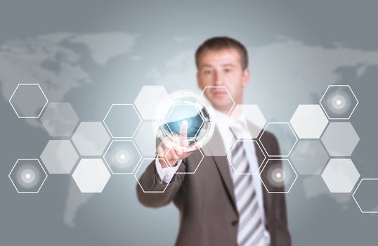 Businessman in suit finger presses virtual button. Transparent hexagons, world map as backdrop