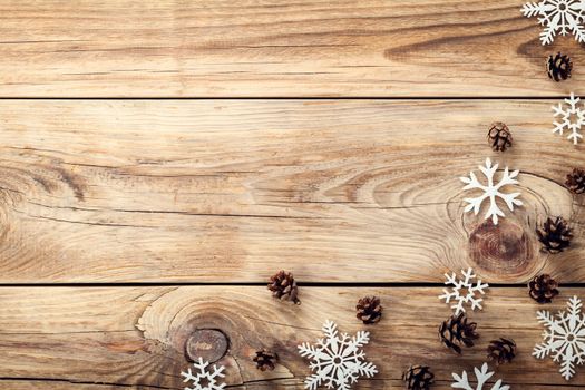 Christmas background with snowflakes and cones on wooden table with copy space. Top view